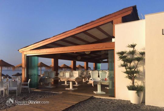 Pérgola de madera para exterior cun cubierta acabada en Brezo y cerramiento en cortina de cristal