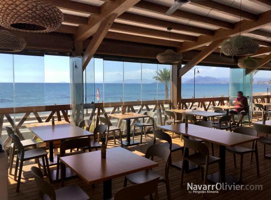 Terraza de madera elevada con cerramiento en cortina de cristal