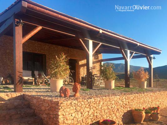 Terraza de casa rural con pérgola de madera y tronco caliobrado