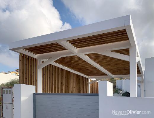 Pérgola de diseño con estructura acabada en blancp, cubierta y muro con emparrillado de madera autoc