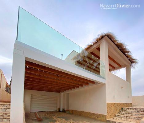 Pérgola de madera con cubierta en carritx terraza y barandilla de cristal