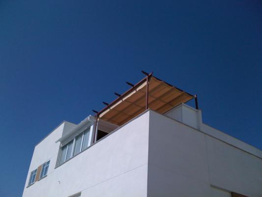 Toldo de guías con estructura en imitación madera.