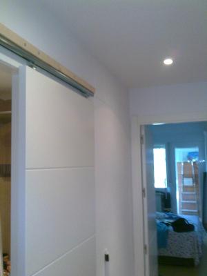 Montaje de puerta corredera deslizante por fuera de tabique lacada en blanco con entrecalles