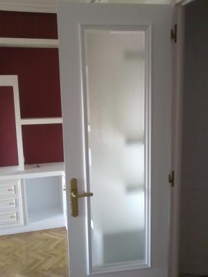 Puerta vidriera restaurada con esmalte blanco y vidrio mateado con bisel