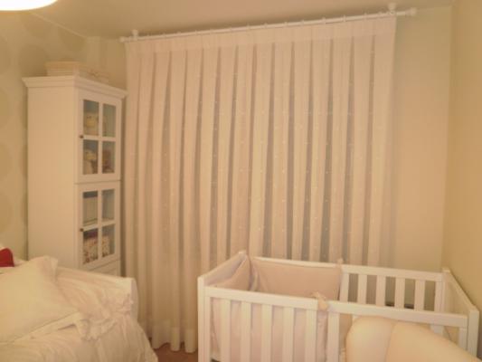 Cortina en tono blanco con detalle de puntitos y sujeta a barra en blanco lacado para habitación inf