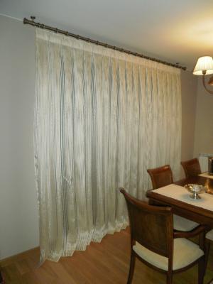 Cortina en tono blanco roto y brillante con barra en bronce.