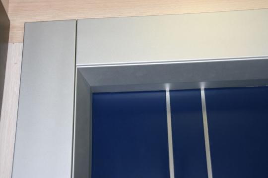 : Detalle del Sistema de unión sin clavos entre marco y tapajuntas en madera natural de haya lacada en aluminio