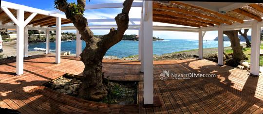 Terraza desmontable junto al mar en madera con suelo en autocleve y cubierta de mimbre